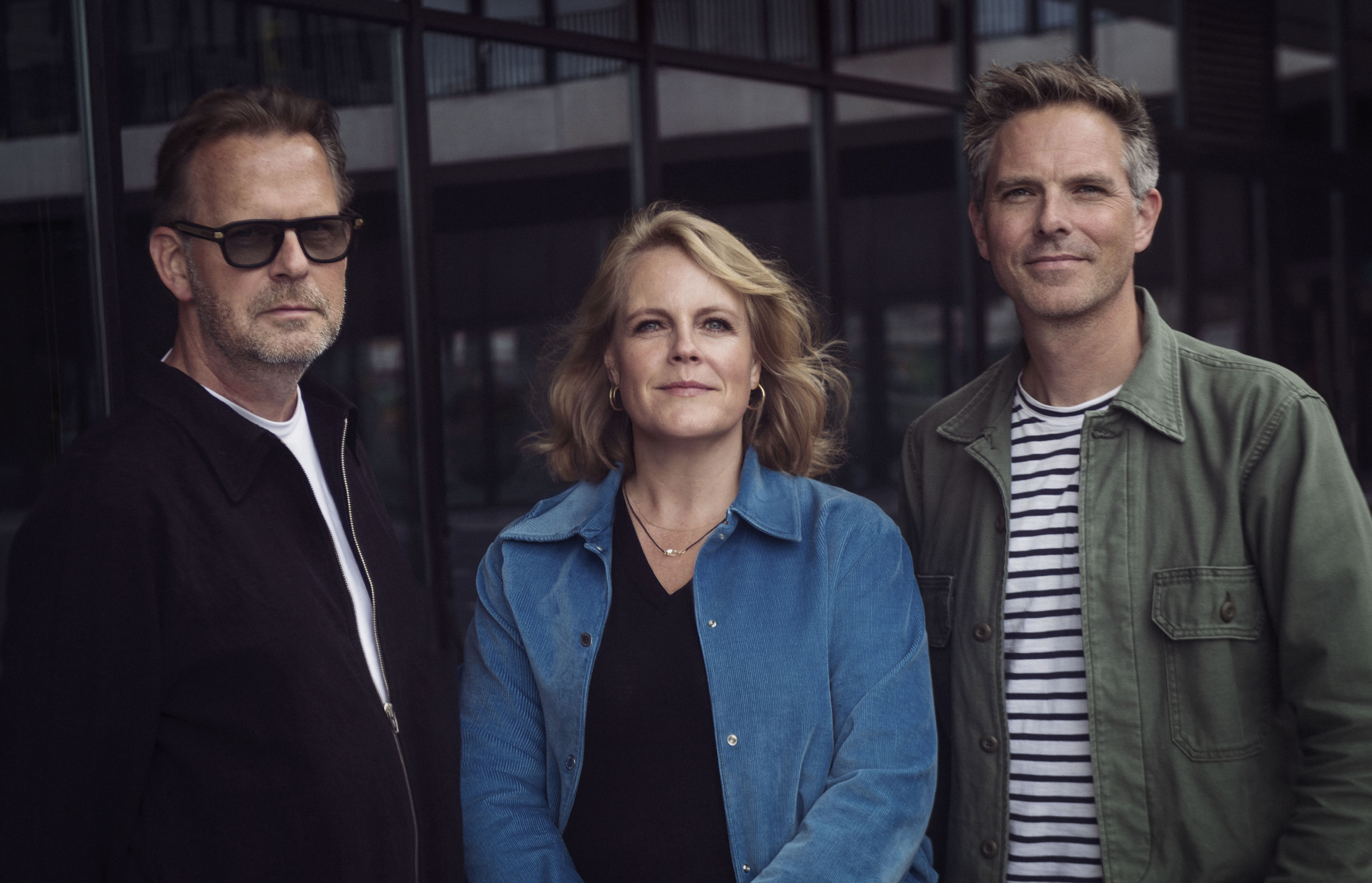 Drie directieleden van MOJO: Ronny Hooch-Antink, Kim Bloem en Ruben Brouwer staand voor glazen gevel.